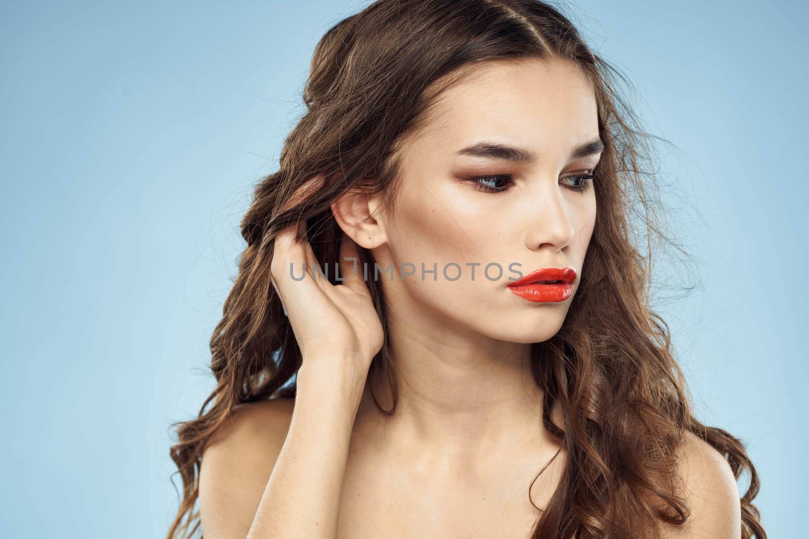 Elegant brunette fashionable hairstyle bright makeup naked shoulders close-up blue background. High quality photo