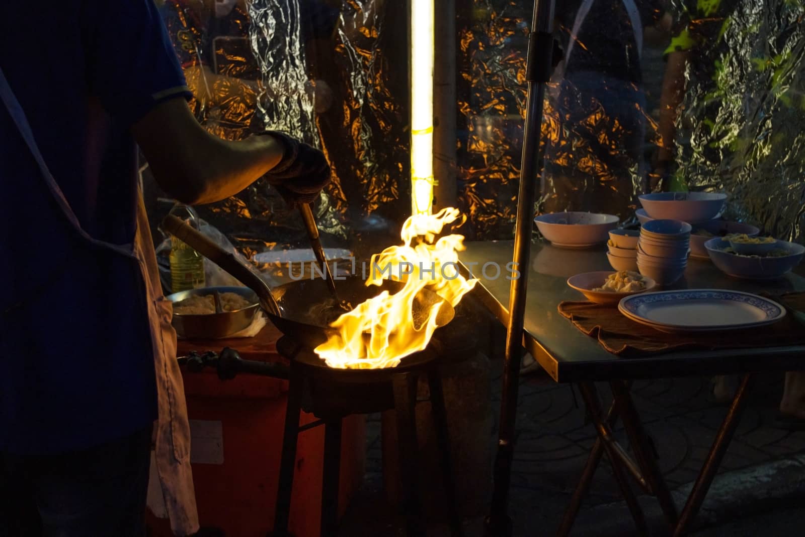 Street food in Bangkok Bangkok Thailand - Oct 24, 2020 :- Chef cooking with fire with frying pan on gas hob at yoawarat Bangkok Thailand.