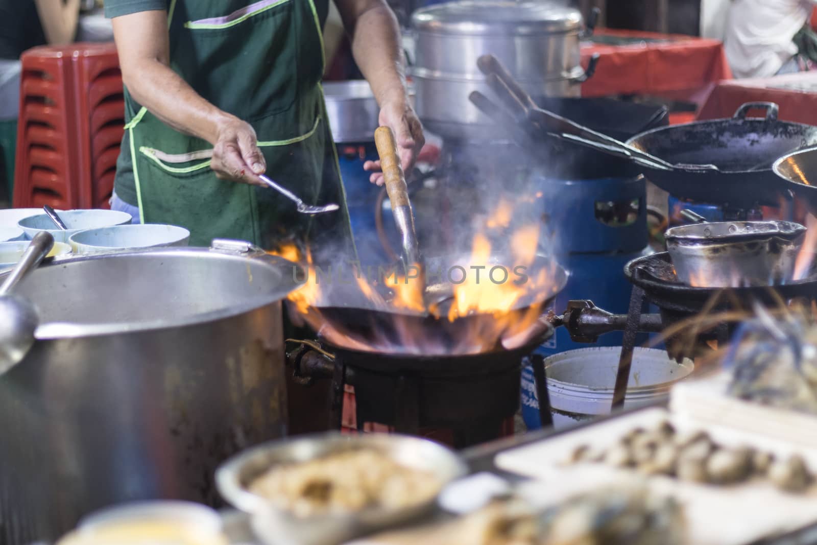 Street food in Bangkok Bangkok Thailand - Oct 24, 2020 :- Chef cooking with fire with frying pan on gas hob at yoawarat Bangkok Thailand.