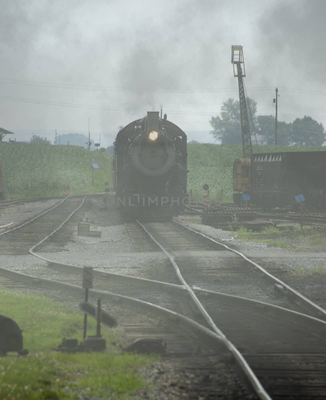 Steam Engine Locomotive with Passenger cars Arriving into Station on a Foggy Day