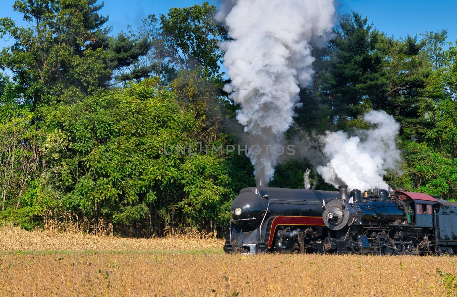 Close up of an 2 Antique Steam Freight Train Puffing Smoke and Steam While going Thru Amish Countryside