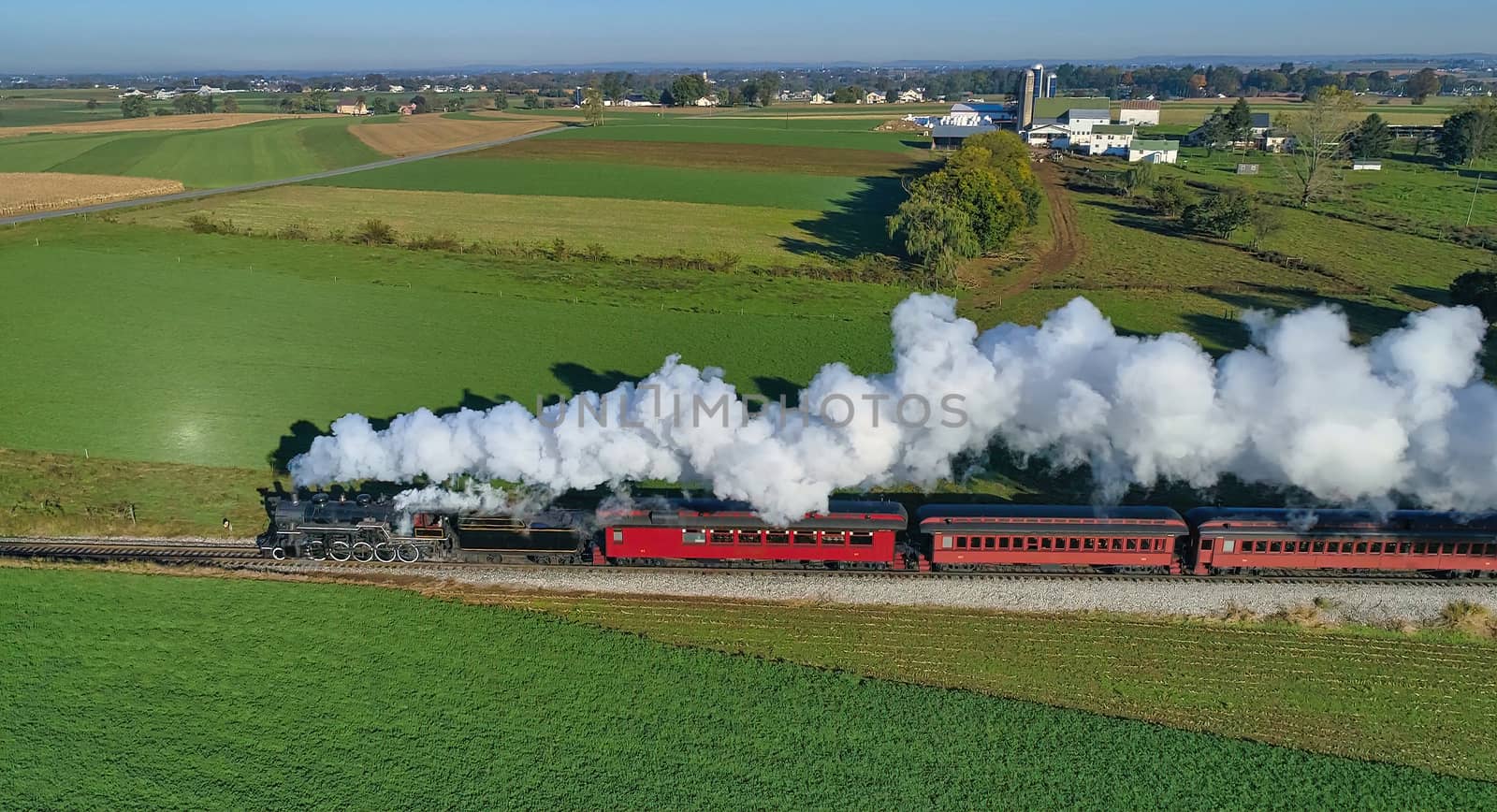 Aerial View of Steam Passenger Train Puffing Smoke Traveling in Amish Countryside in an Early Morning