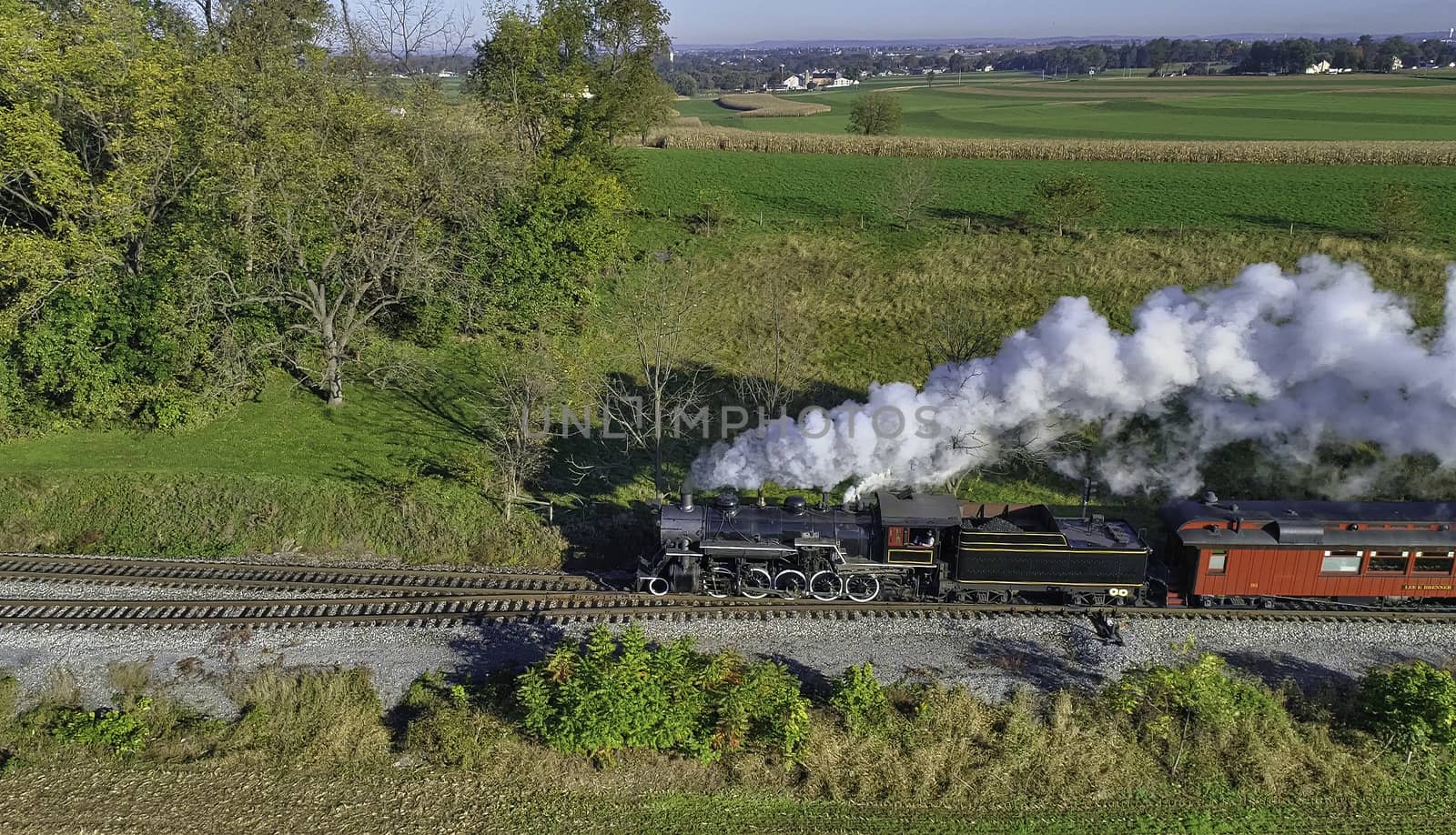 Aerial View of Steam Passenger Train Puffing Smoke Traveling in Amish Countryside in an Early Morning