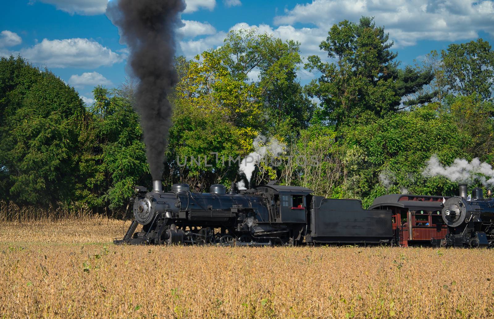 Close up of an Antique Steam Freight Train Puffing Smoke and Steam While going Thru Amish Countryside