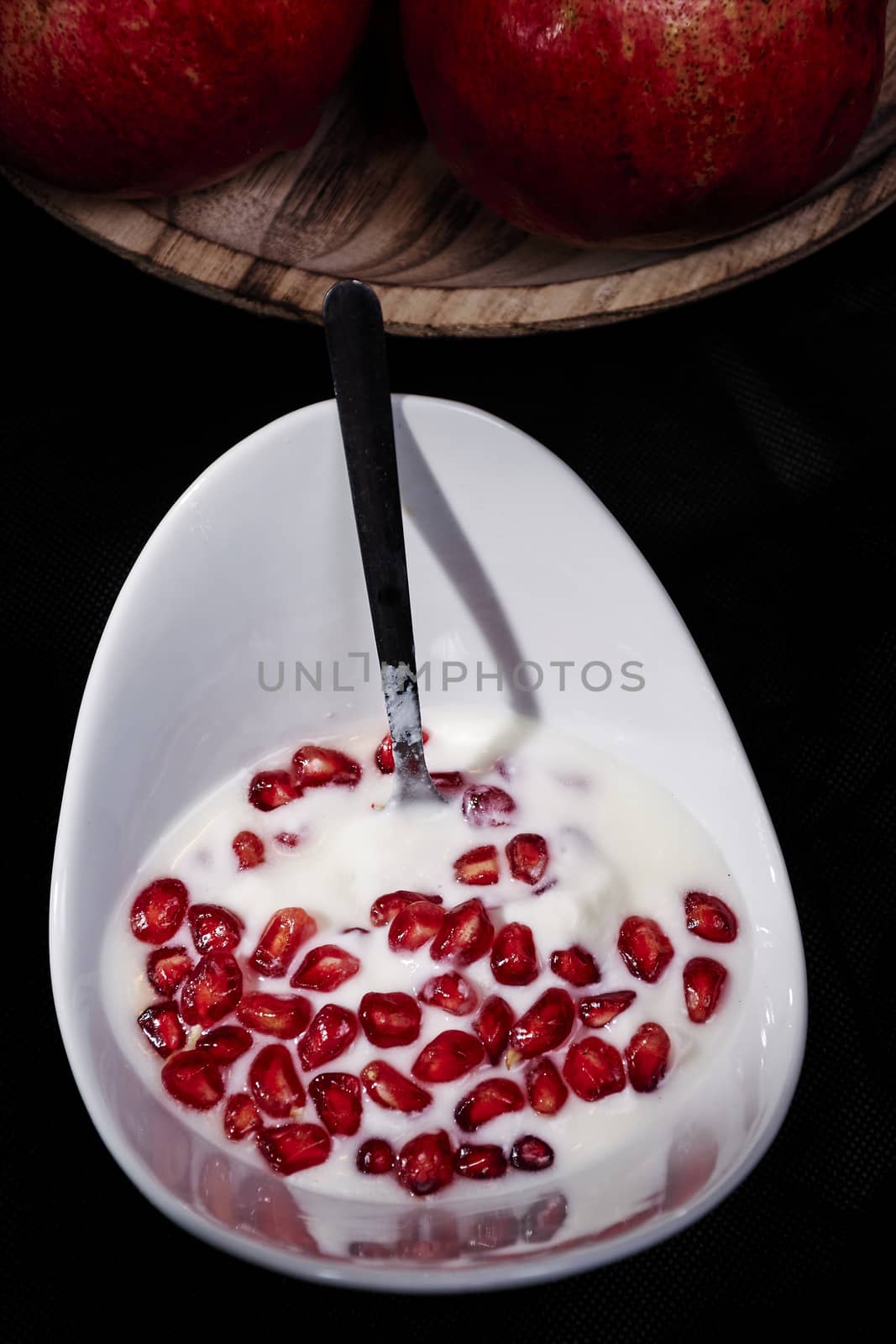 Bowl of pomegranate seeds with yogurt, macro photography