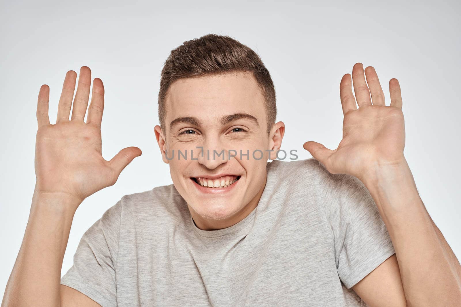 Cheerful emotional man gray t-shirt gesturing with hands studio lifestyle. High quality photo