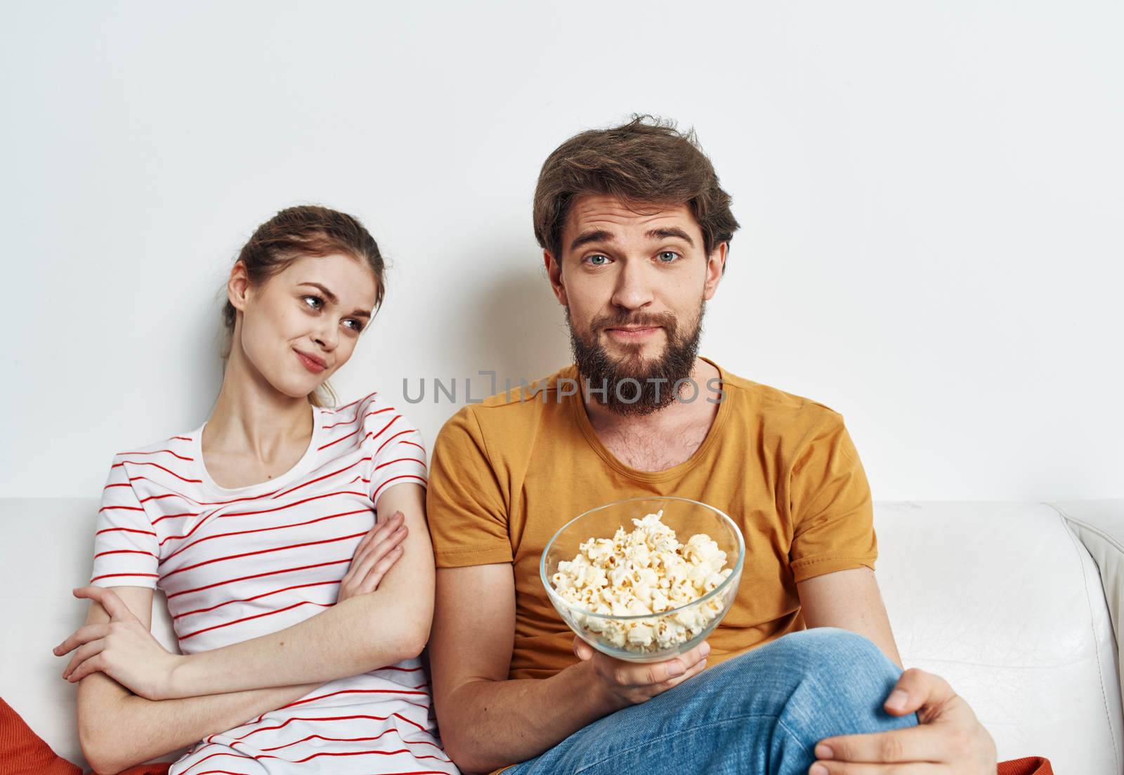 Man and woman on the couch with popcorn watching TV shows. High quality photo