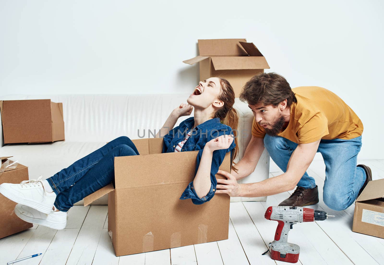 Man and woman boxes with things white sofa interior moving room. High quality photo