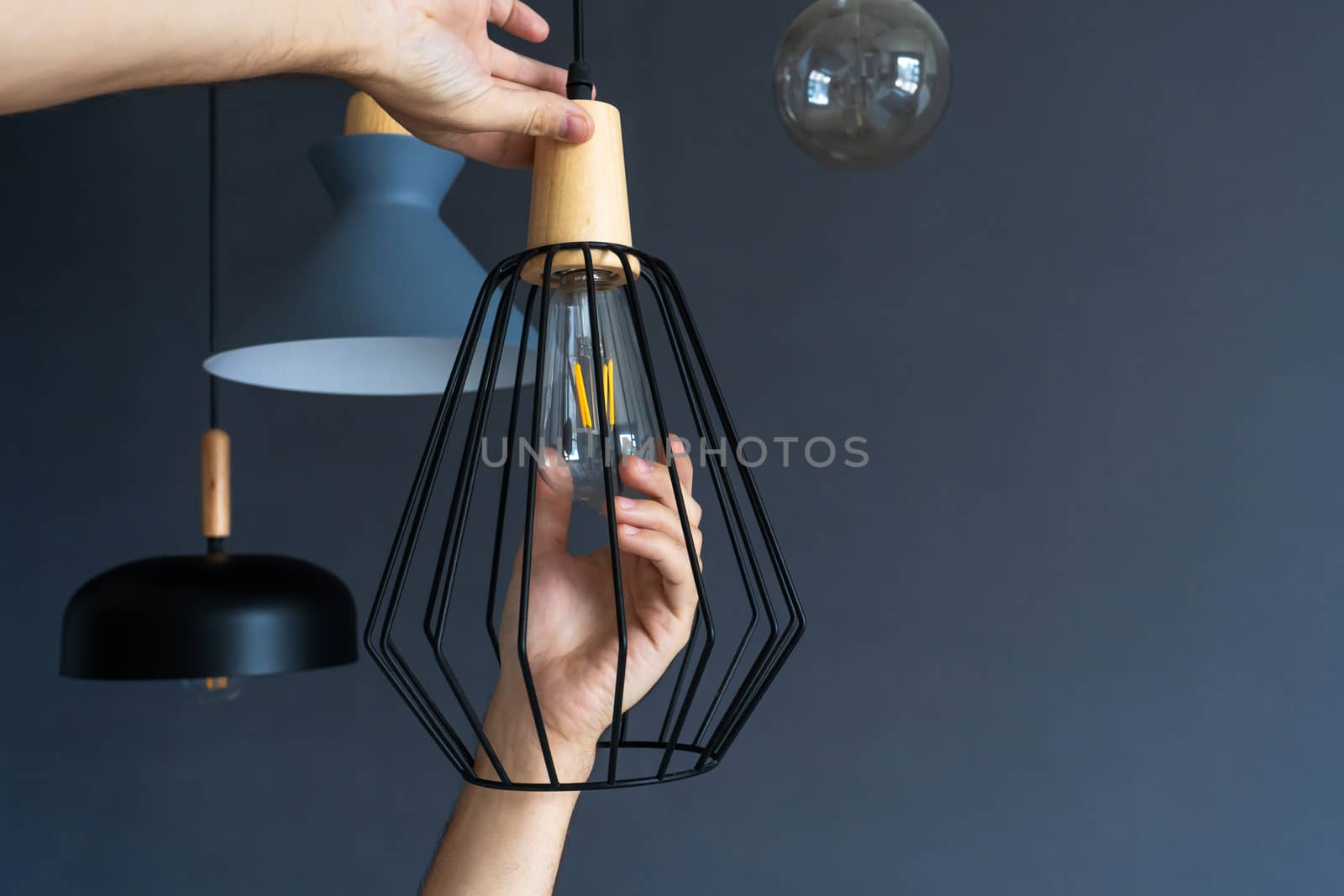 Close-up. A hand changes a light bulb in a stylish loft lamp. Spiral filament lamp. Modern interior decor. by Try_my_best