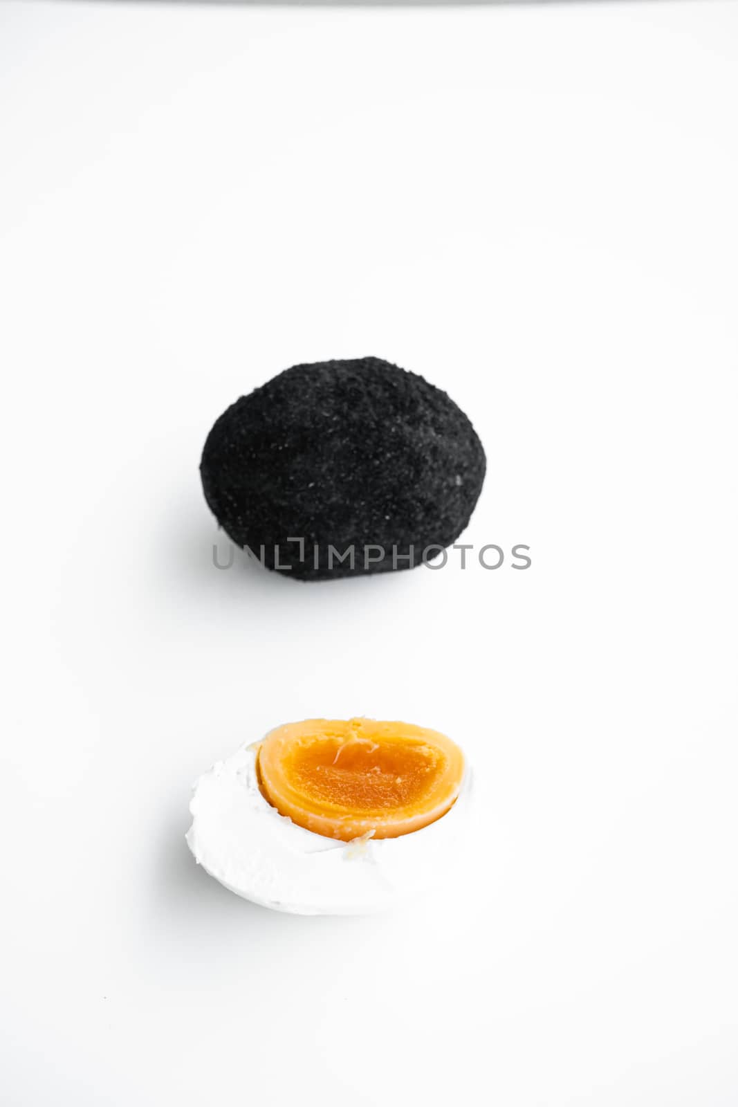 An old duck egg recipe in ash. Salty pickled duck egg in ash on a white background.