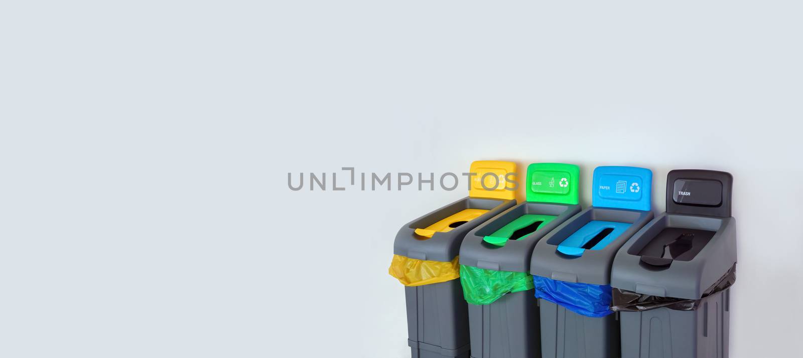 Different colored bins for collection of recycled materials. Green, Yellow, Blue, Black color plastic garbage recycle bin. Separate sorting of garbage. Types of Waste Plastic, Glass, Paper, Trash by synel