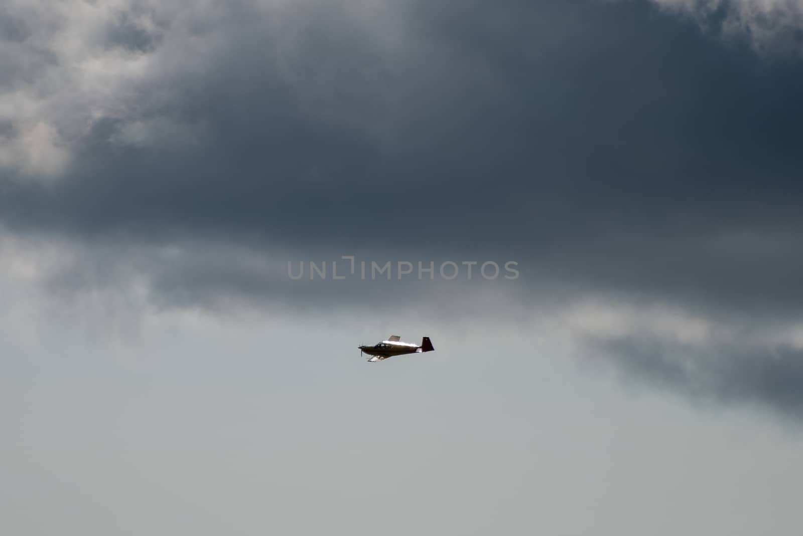 Silhouette of a light aircraft in a cloudy sky.
