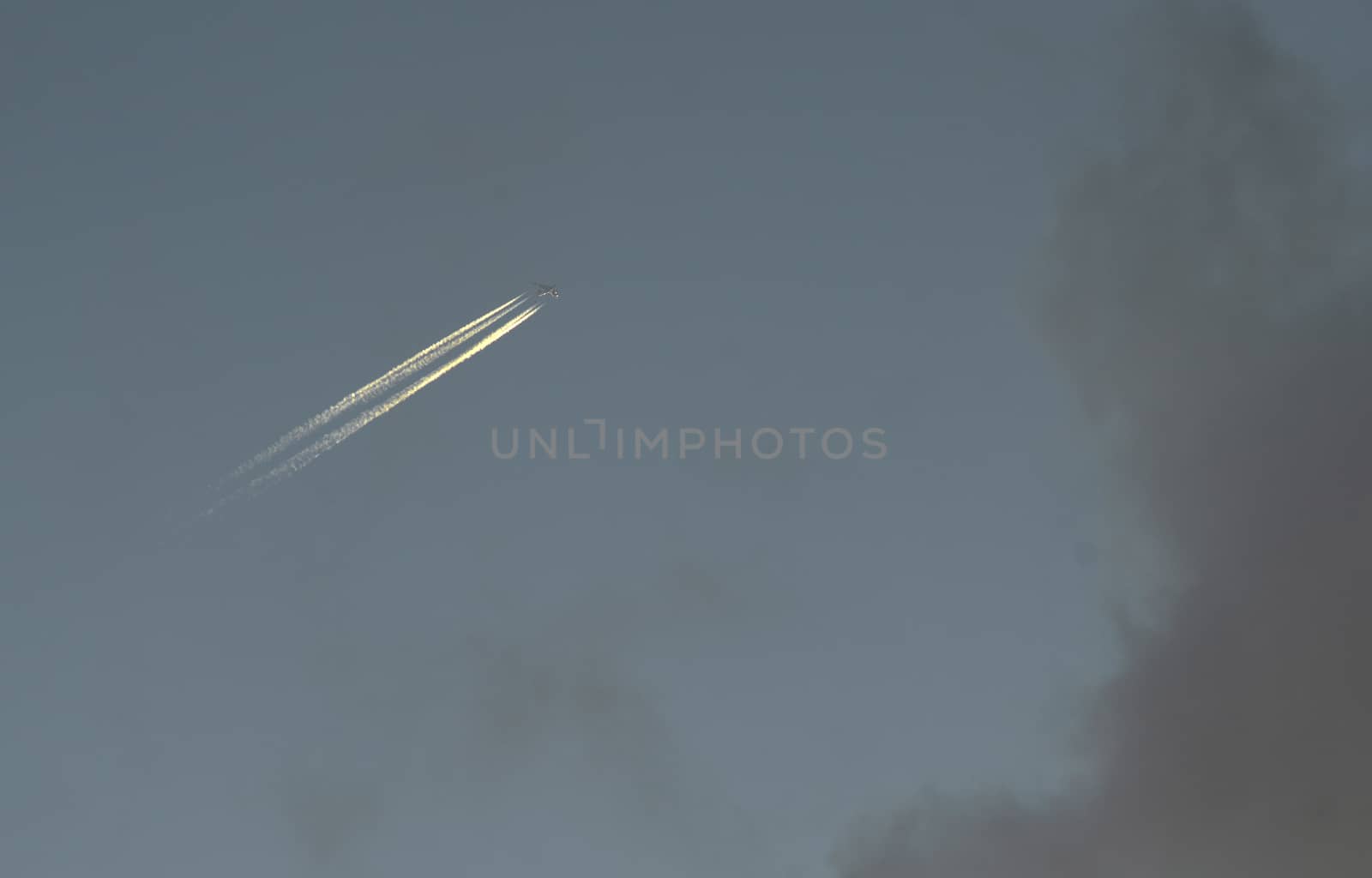 A plane with a reversible trail following it in the blue sky.