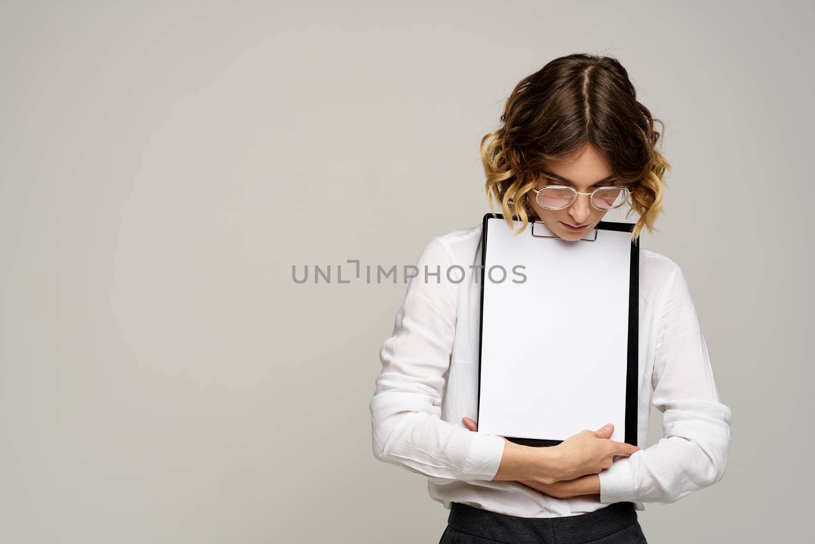 Business woman in a light shirt and a folder with documents in hands cropped view of work. High quality photo