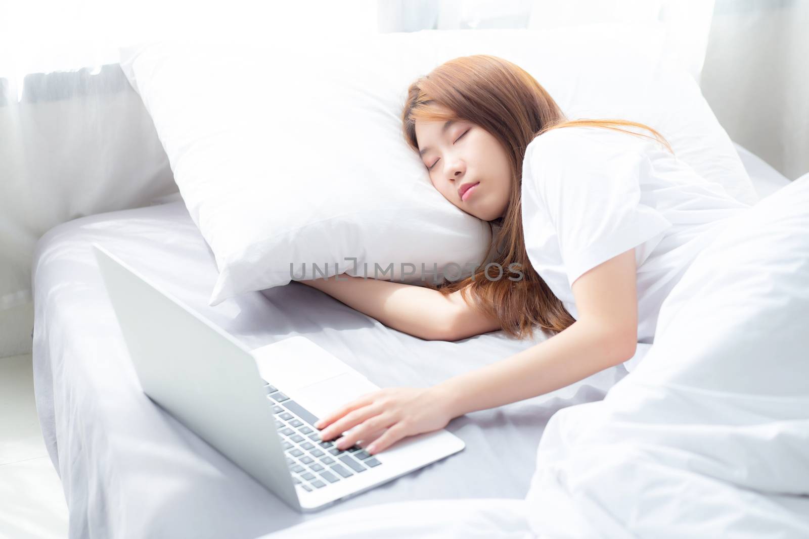 Beautiful of portrait young asian woman with laptop lying down in bedroom, girl tired sleep and relax with computer notebook, resting and healthcare concept.