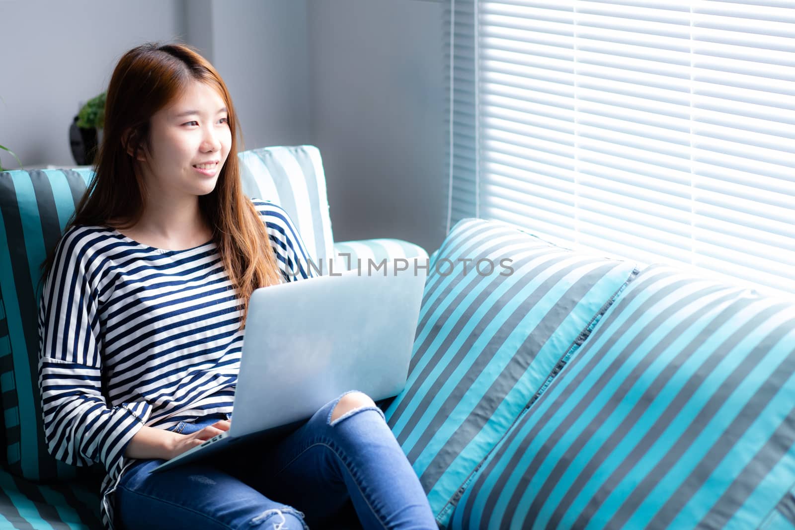 Beautiful of portrait young asian woman using laptop for leisure on sofa in living room, girl working online with notebook freelance with a happy, communication business concept.