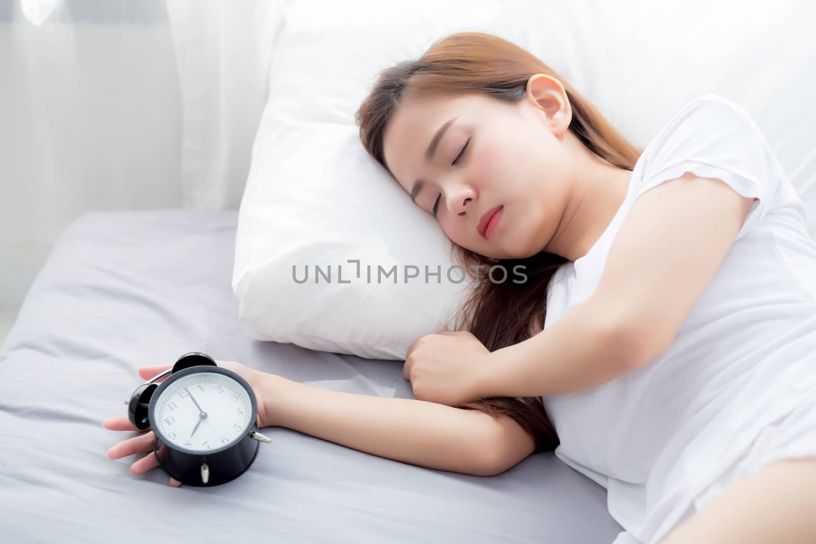 Beautiful asian young woman turn off alarm clock in good morning, wake up for sleep, girl holding alarm clock, time and lifestyle concept.