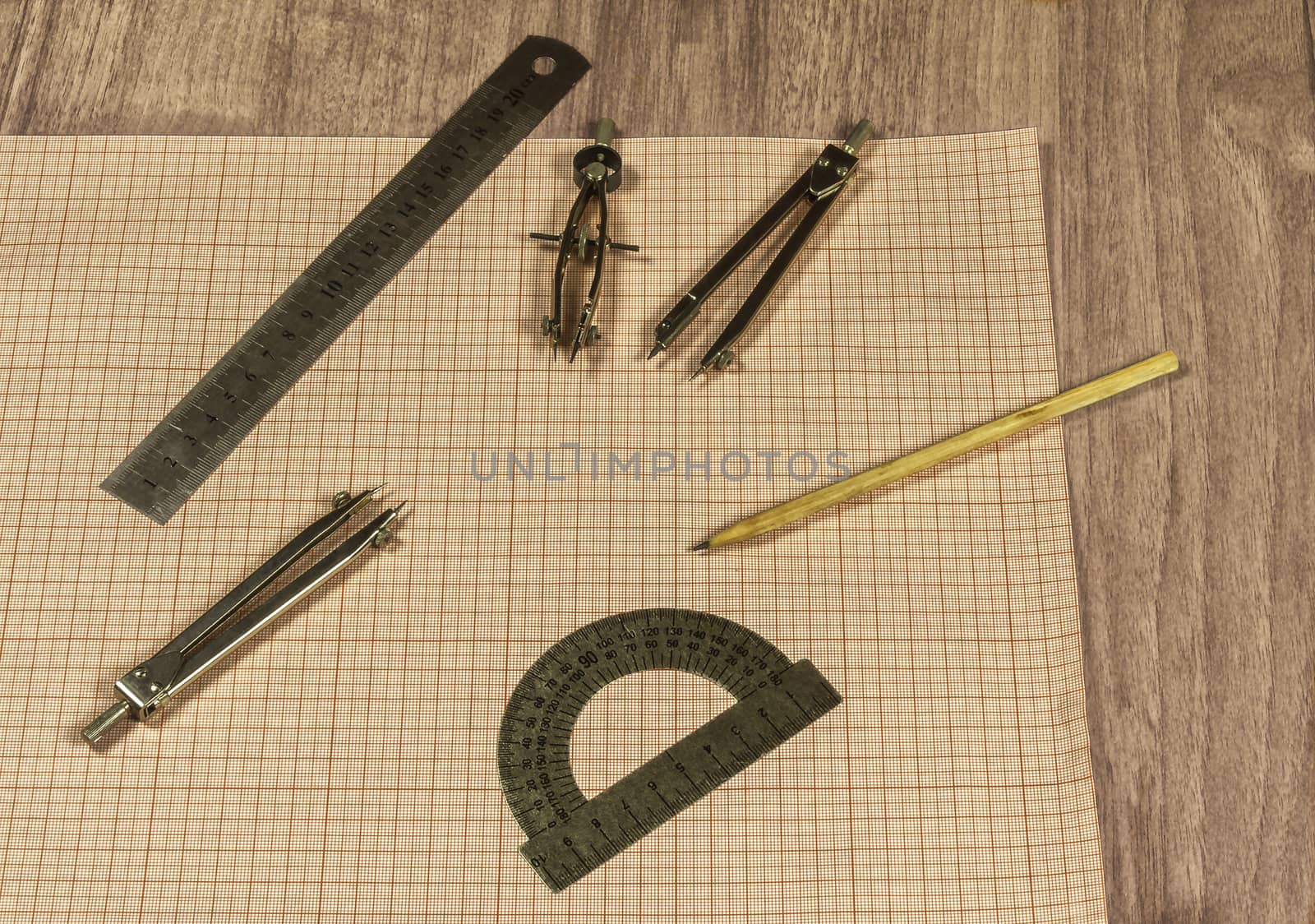 Drawing accessories and millimeter paper lie on a wooden surface by Grommik