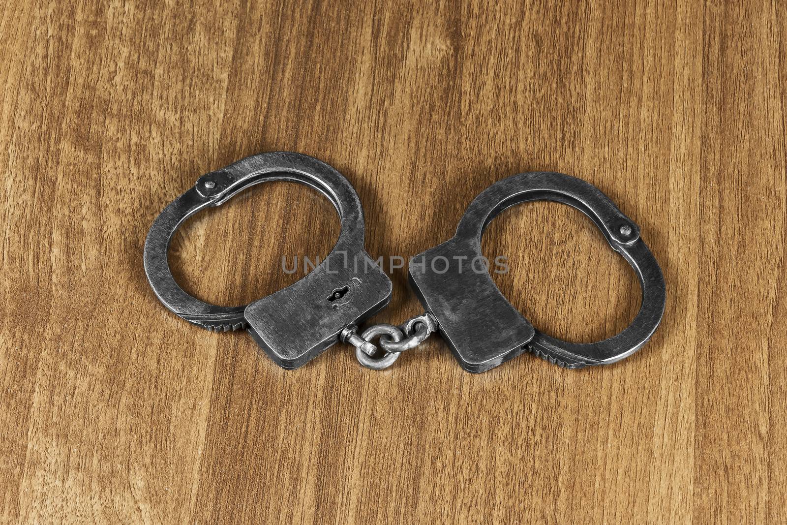 On the wooden table lie the police handcuffs by Grommik