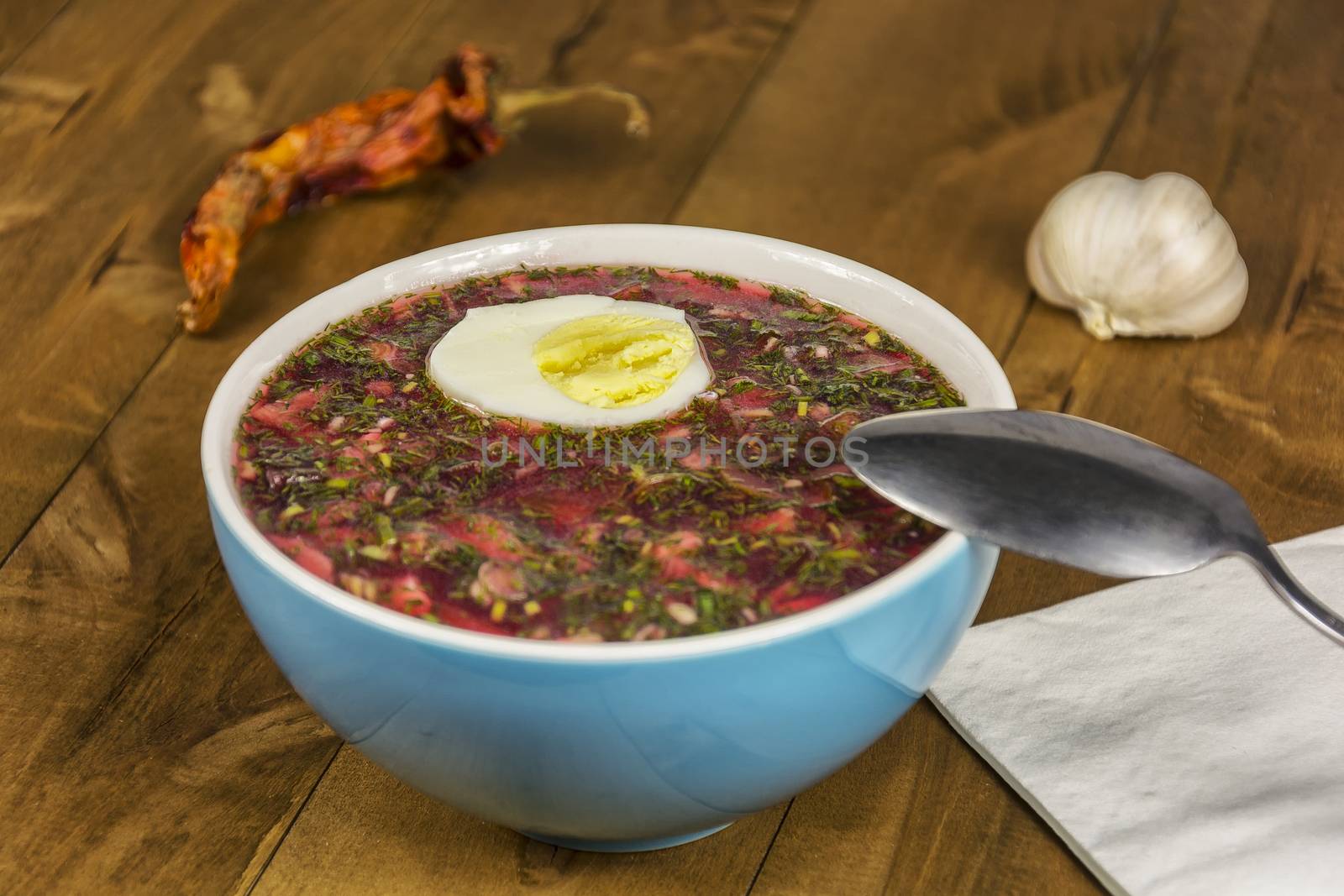 Cold vegetable soup with egg on a wooden table by Grommik