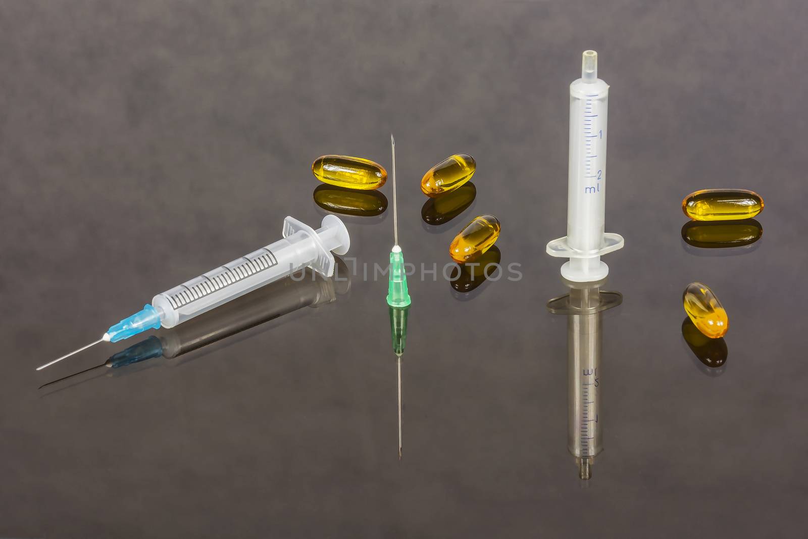 Two medical syringes with needles and capsules with medicine by Grommik