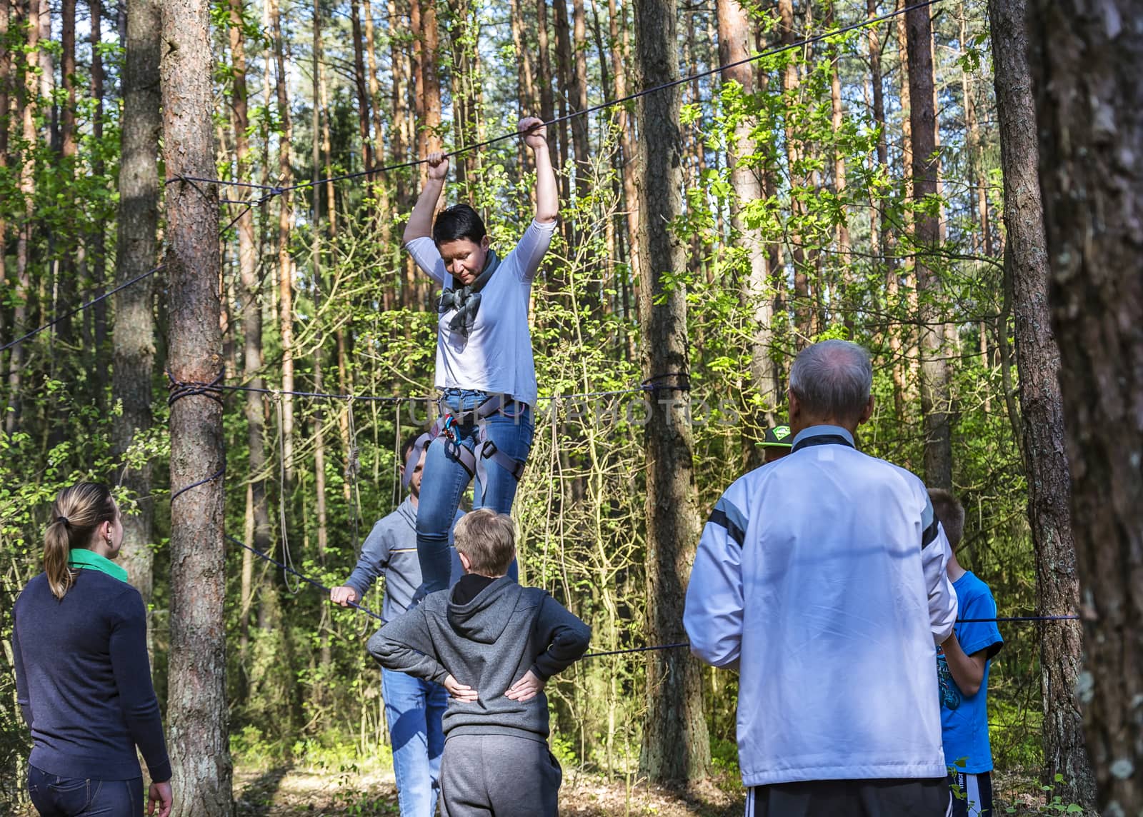 A woman trains to walk on a tight rope with insurance by Grommik