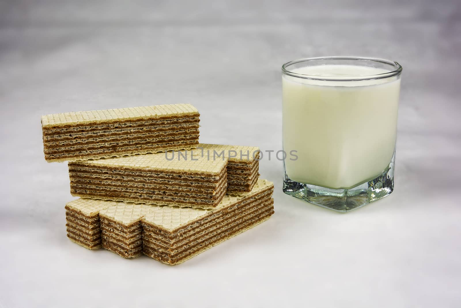 A glass of yogurt and wafers with chocolate filling on a gray background