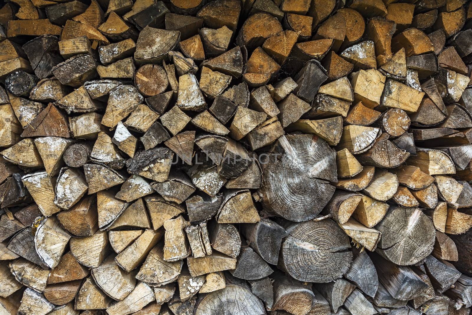 The firewood is packed in a woodpile for the winter season