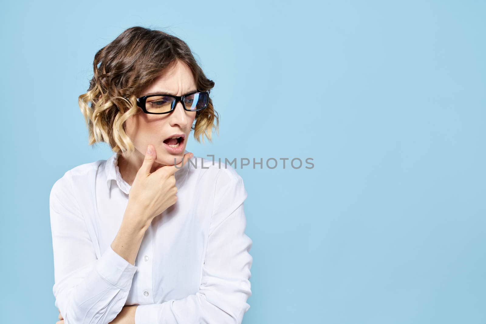 Business woman in a light shirt on a blue background gestures with her hands emotions model work. High quality photo