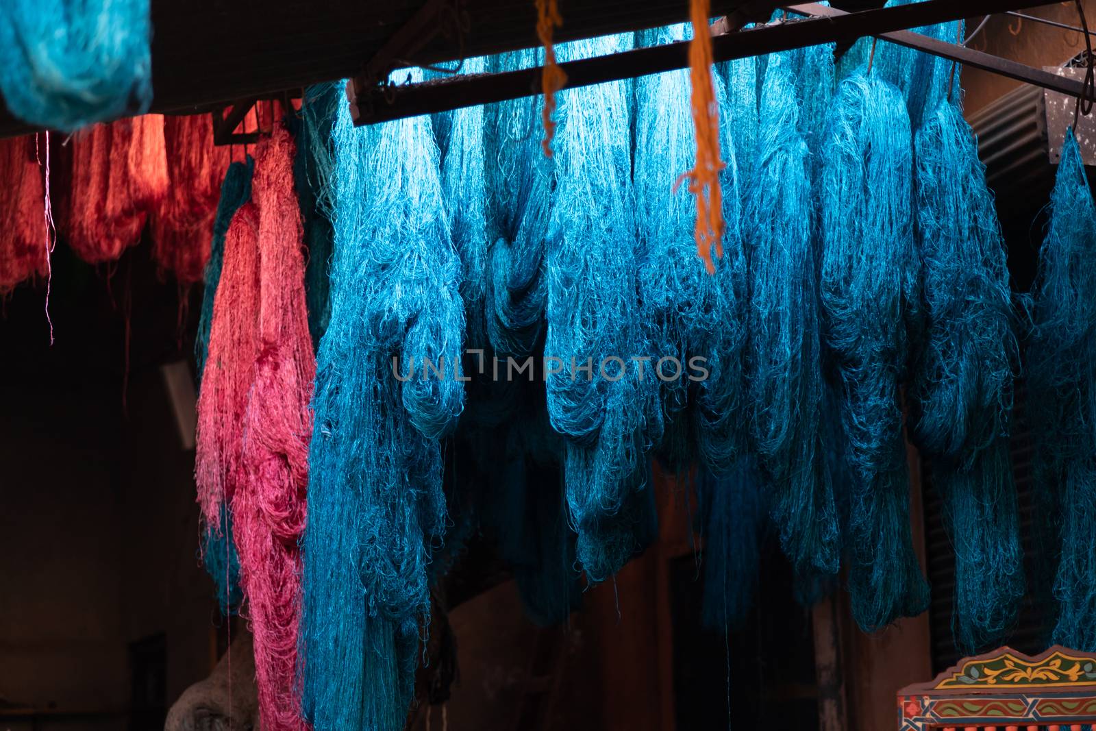 Dyed wool hanging to dry in souk in Marrakech Morocco, red, blue, yellow, gold by kgboxford