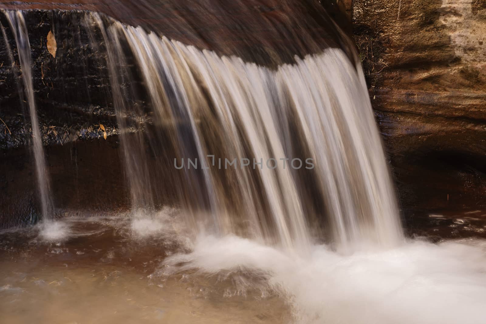 Beautiful waterfall streaming over red colored bedrock in the Left Fork North Creek, Zion National Park.