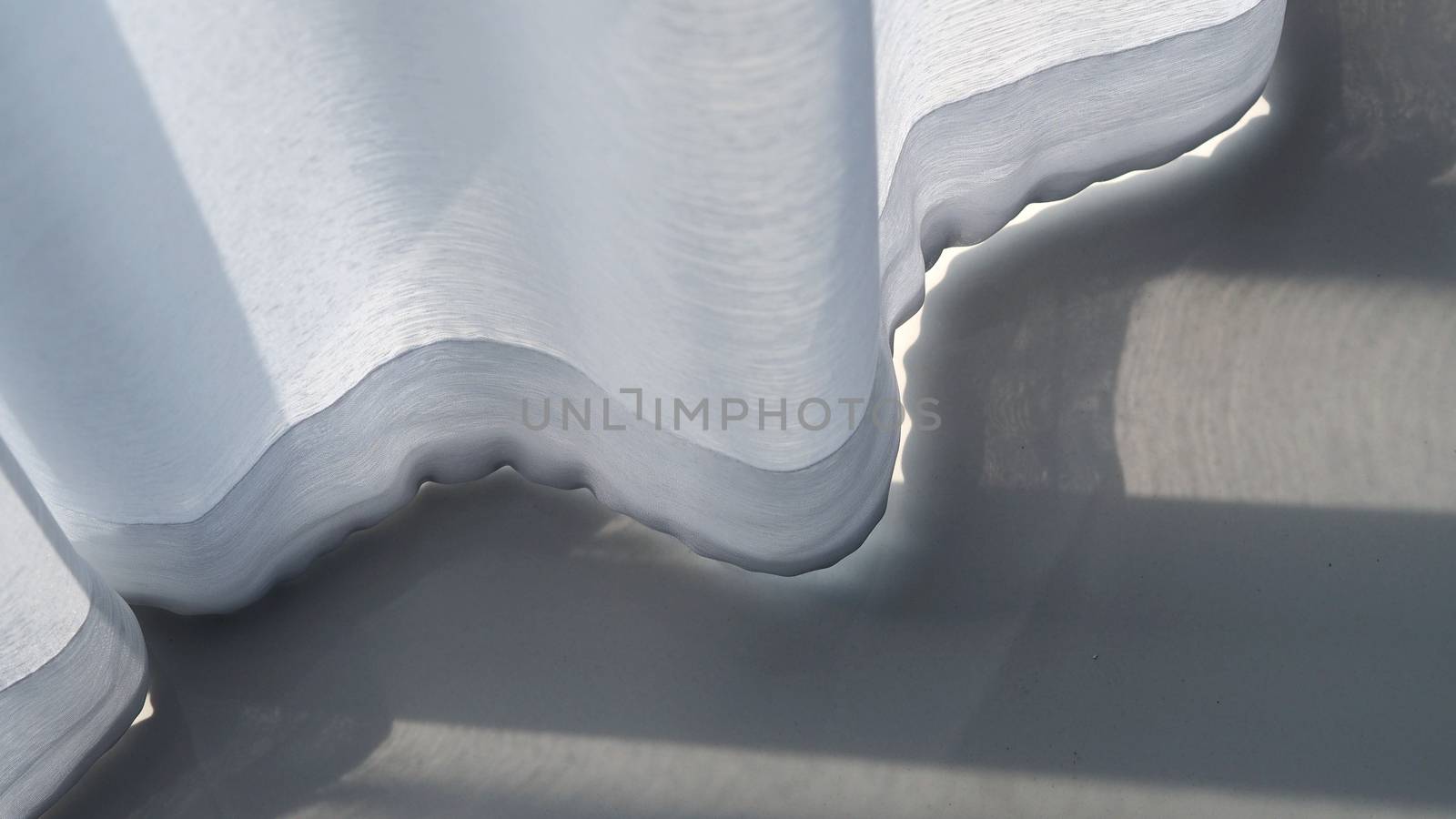 White curtain blowed by wind and grey color ceramic floor tiles texture close-up and top view angle.