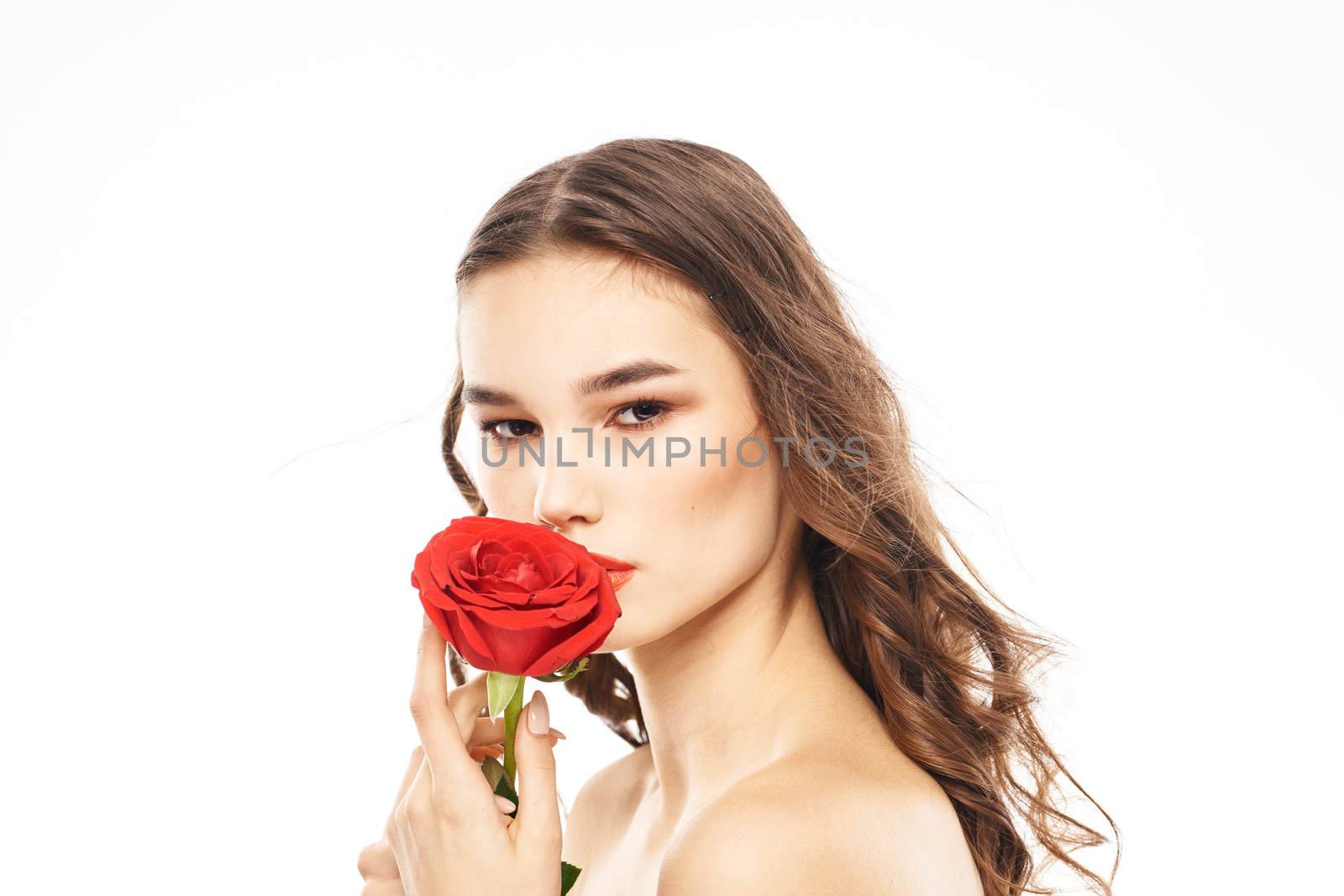 Woman with naked shoulders and red rose evening makeup light background. High quality photo