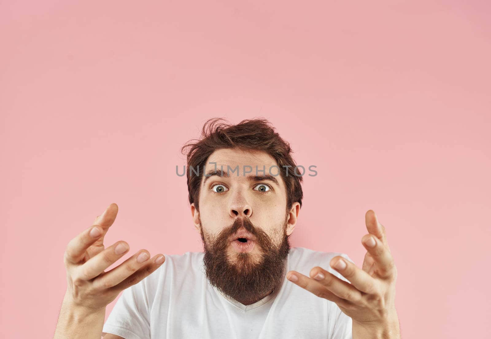 man emotions model gesturing with hands pink background close-up. High quality photo