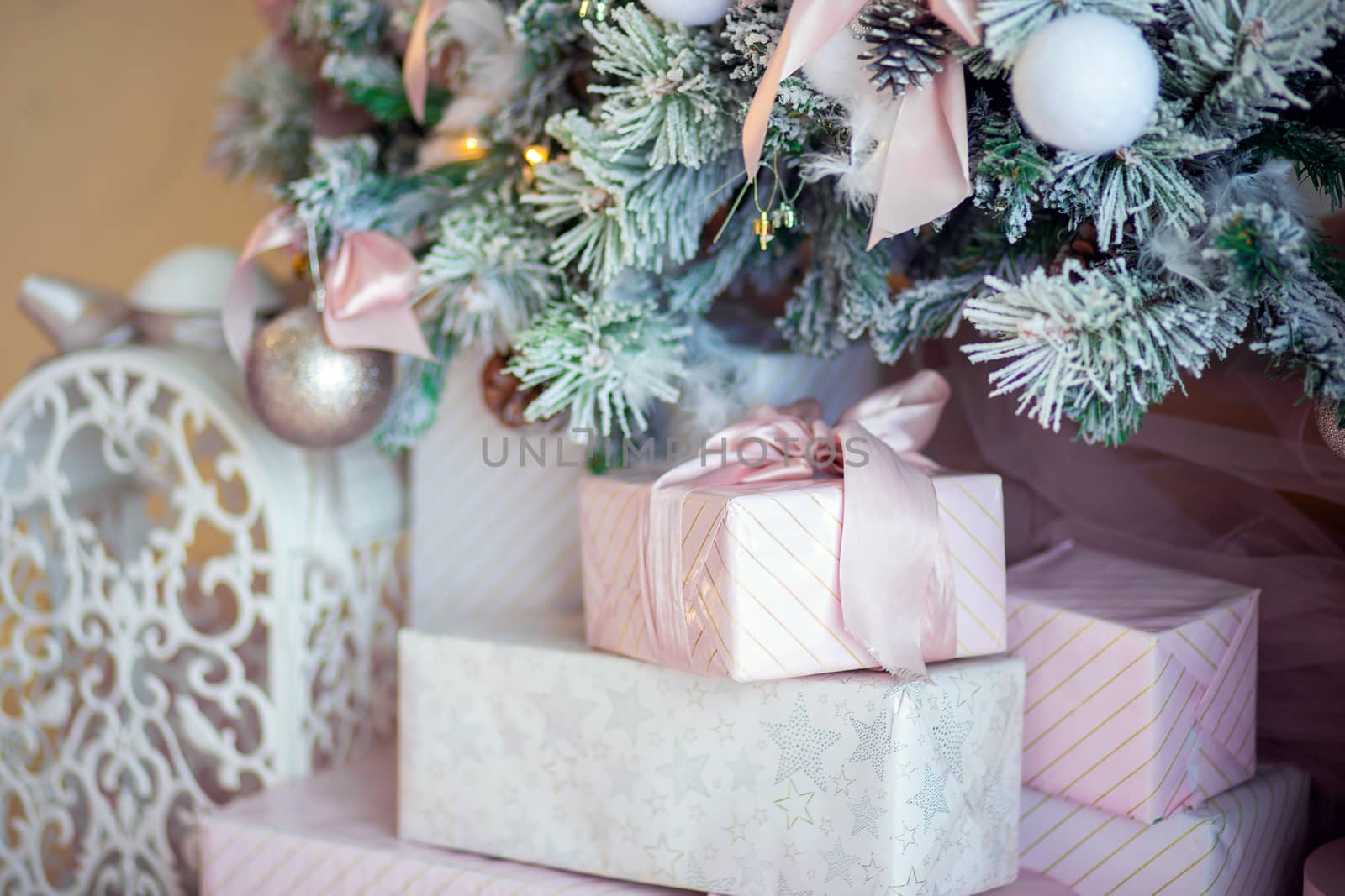 Beautifully wrapped gifts lie under a Christmas tree decorated in a modern twist in soft pink