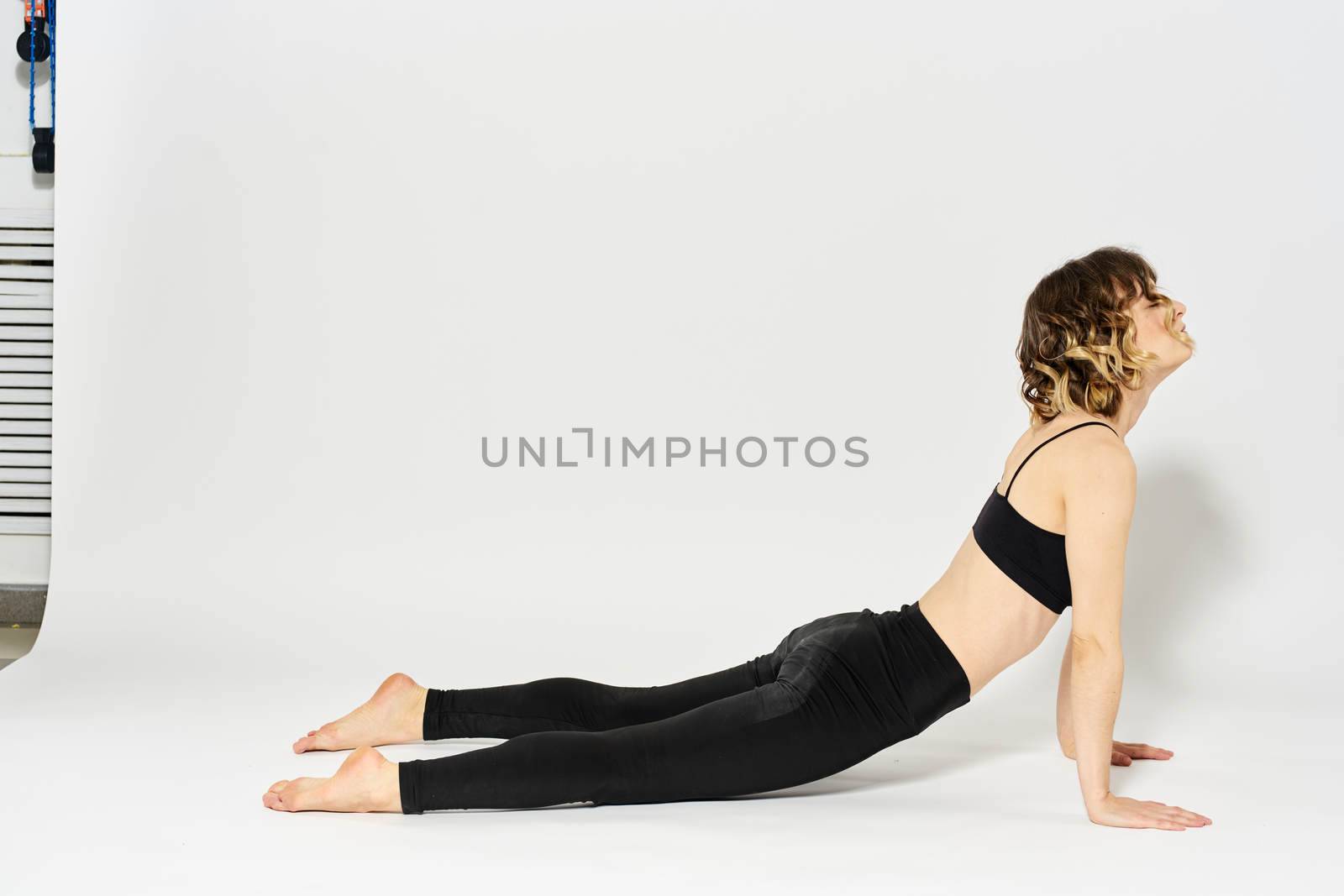 Sportive woman will do the exercise lying on the floor Gymnastics fitness in a bright room. High quality photo
