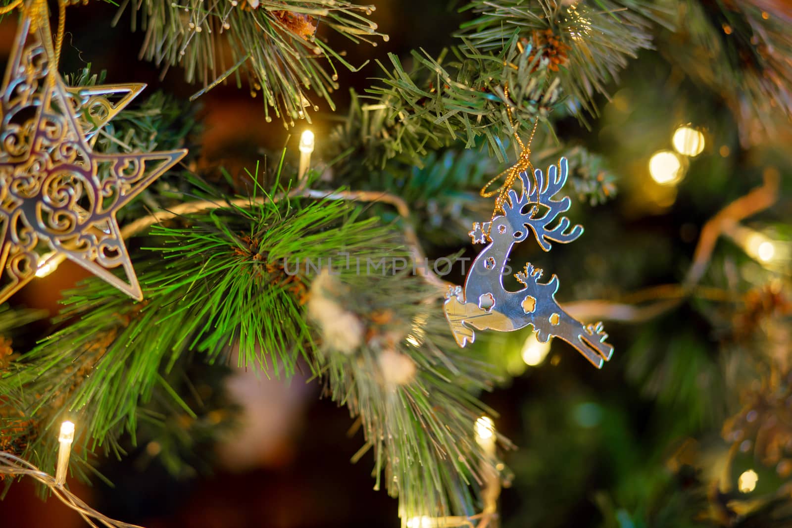 Christmas decoration in the form of a galloping deer on a Christmas tree. Golden deer, Christmas tree toy on a branch of a festive tree