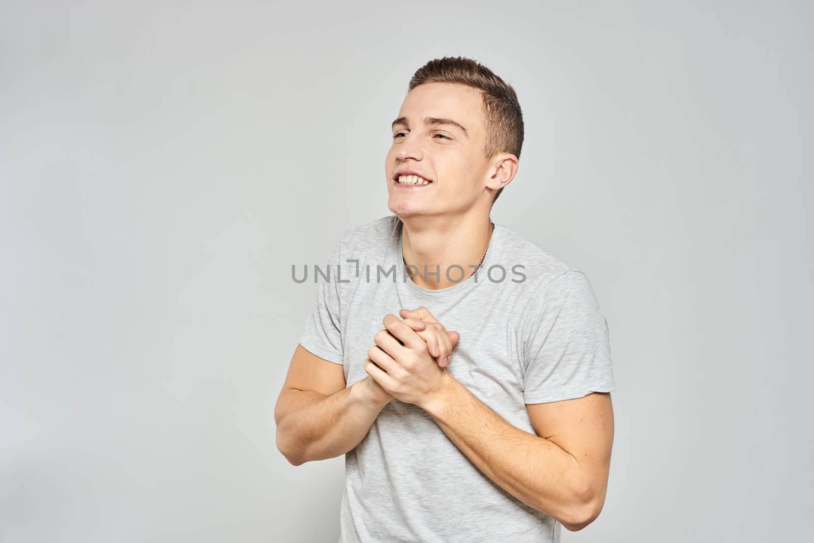 handsome man in light t-shirt cropped view emotion studio isolated background by SHOTPRIME