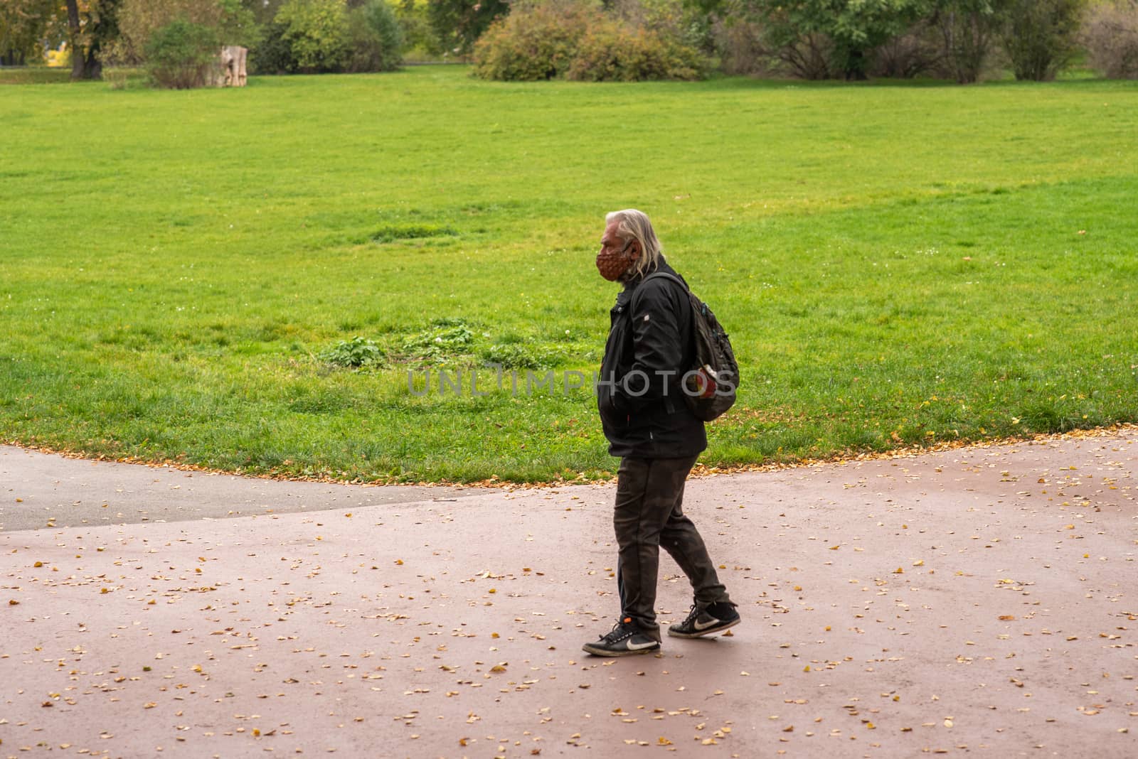 Old man with mask walking in the park in Prague. Editorial.