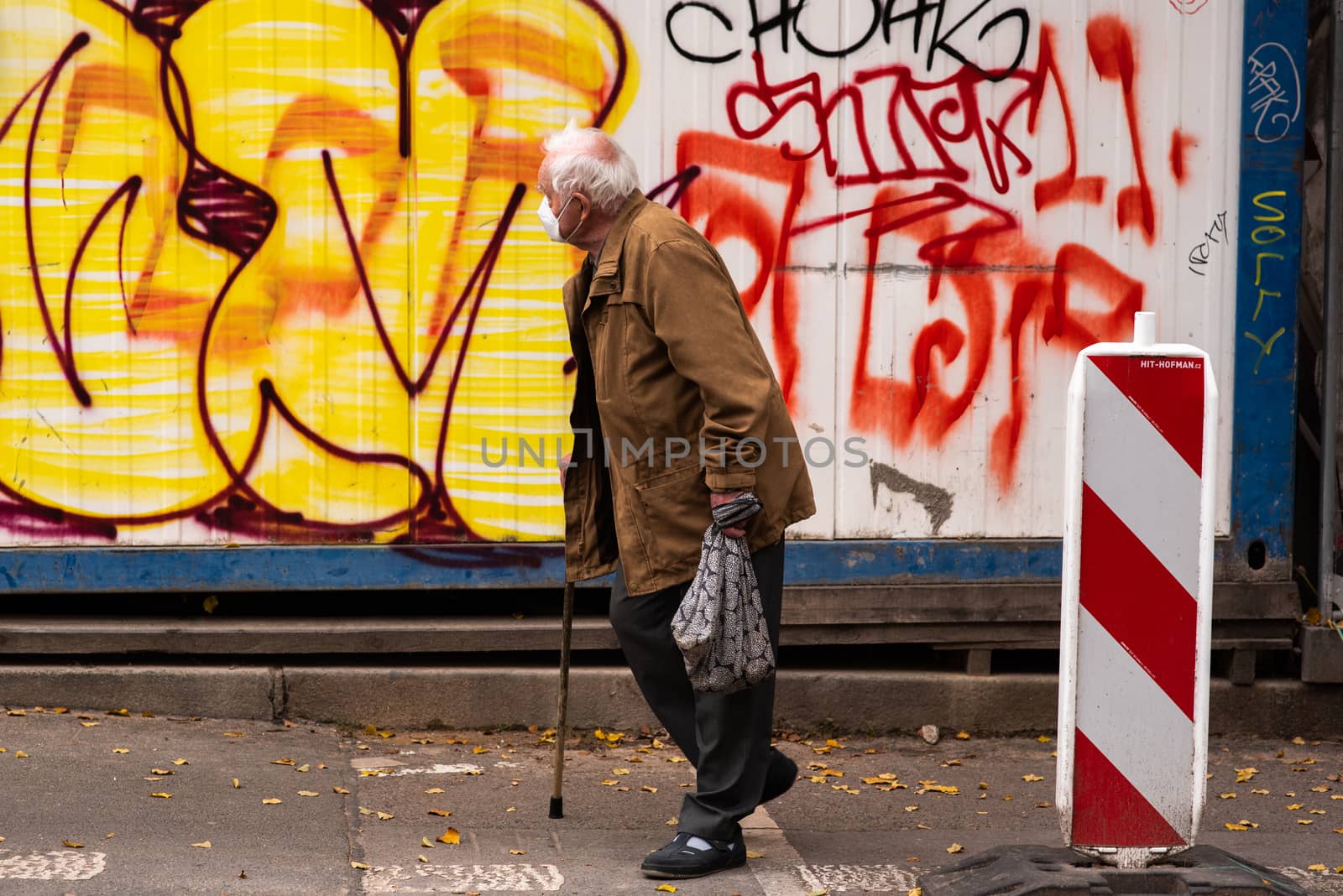 Old man with mask walking with walking stick in the park in Prague by gonzalobell