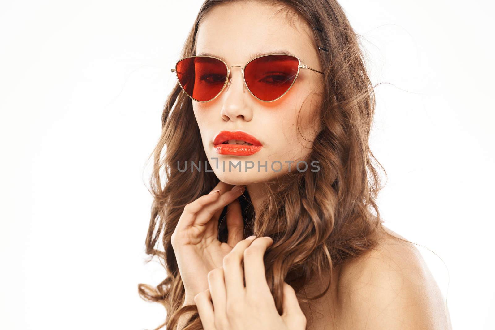 Portrait of brunette woman in sunglasses naked shoulders light background. High quality photo