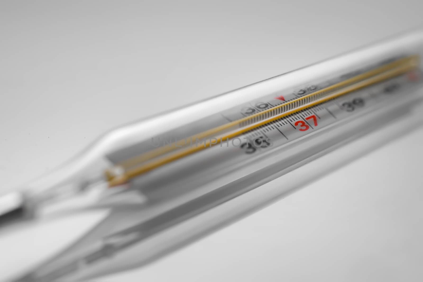 Mercury thermometer. Selective focus, gray background. by 9parusnikov