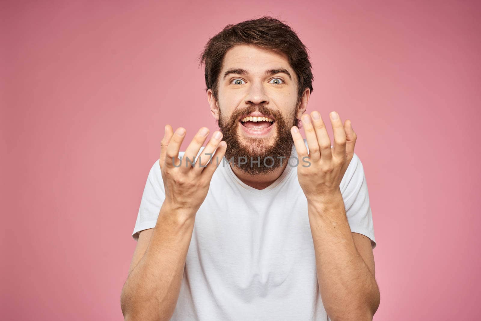 man in white t-shirt gesturing with his hands emotions fun pink background. High quality photo