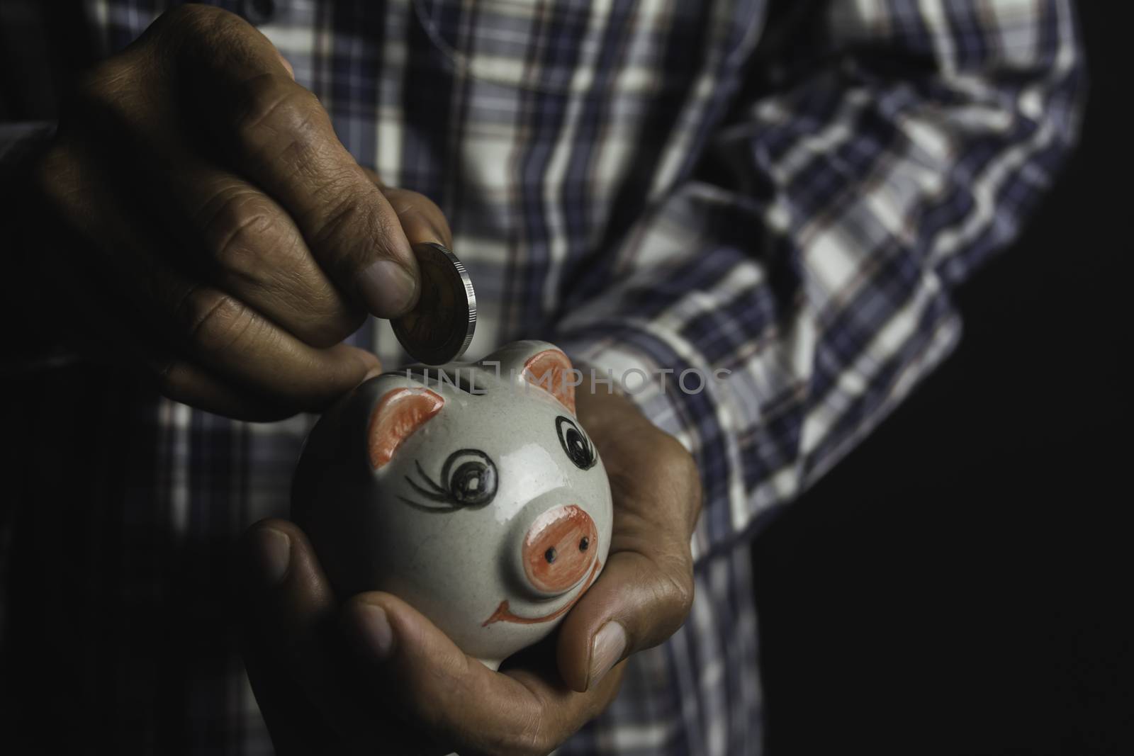 Saving money concept and hand putting money coin into piggy bank by kirisa99