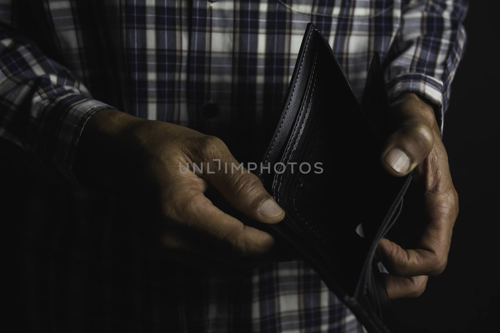 Close-up for a man standing and holding empty wallet. Wallet out of money.