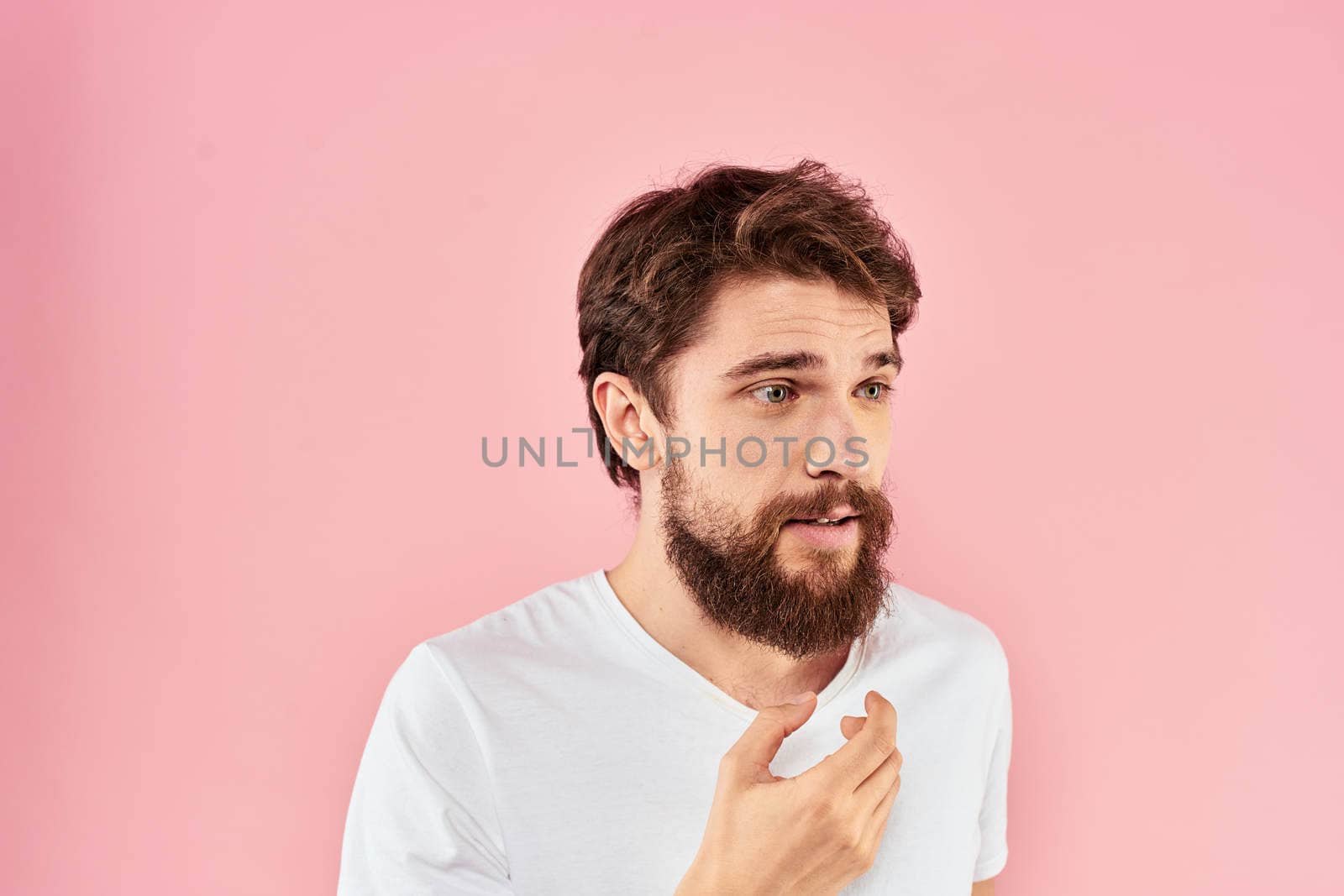 Man in white t-shirt gestures with hands emotions lifestyle cropped view pink background. High quality photo