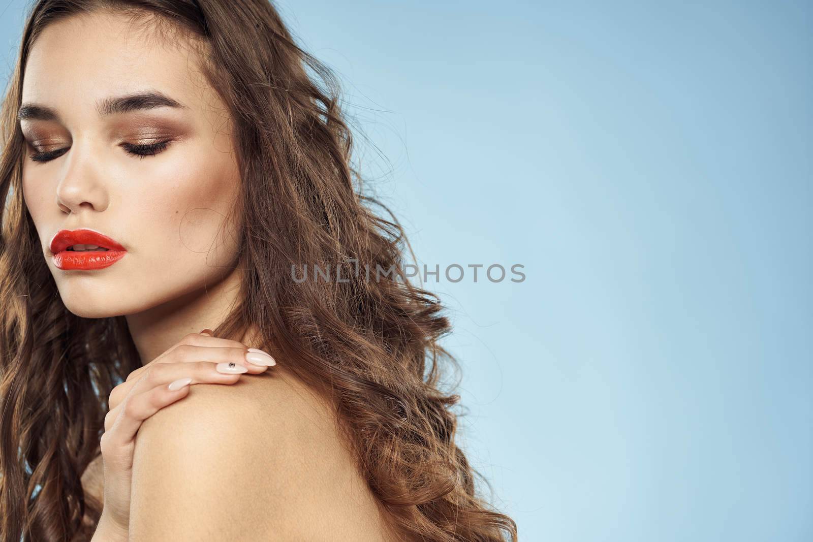 Beautiful woman naked shoulders hairstyle care bright makeup blue background. High quality photo