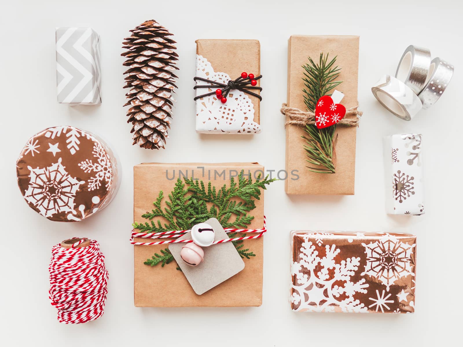 Christmas DIY presents wrapped in craft paper with fir tree twigs and red heart and bells. Top view on decorations on New Year gifts. Festive background. Winter holiday spirit.