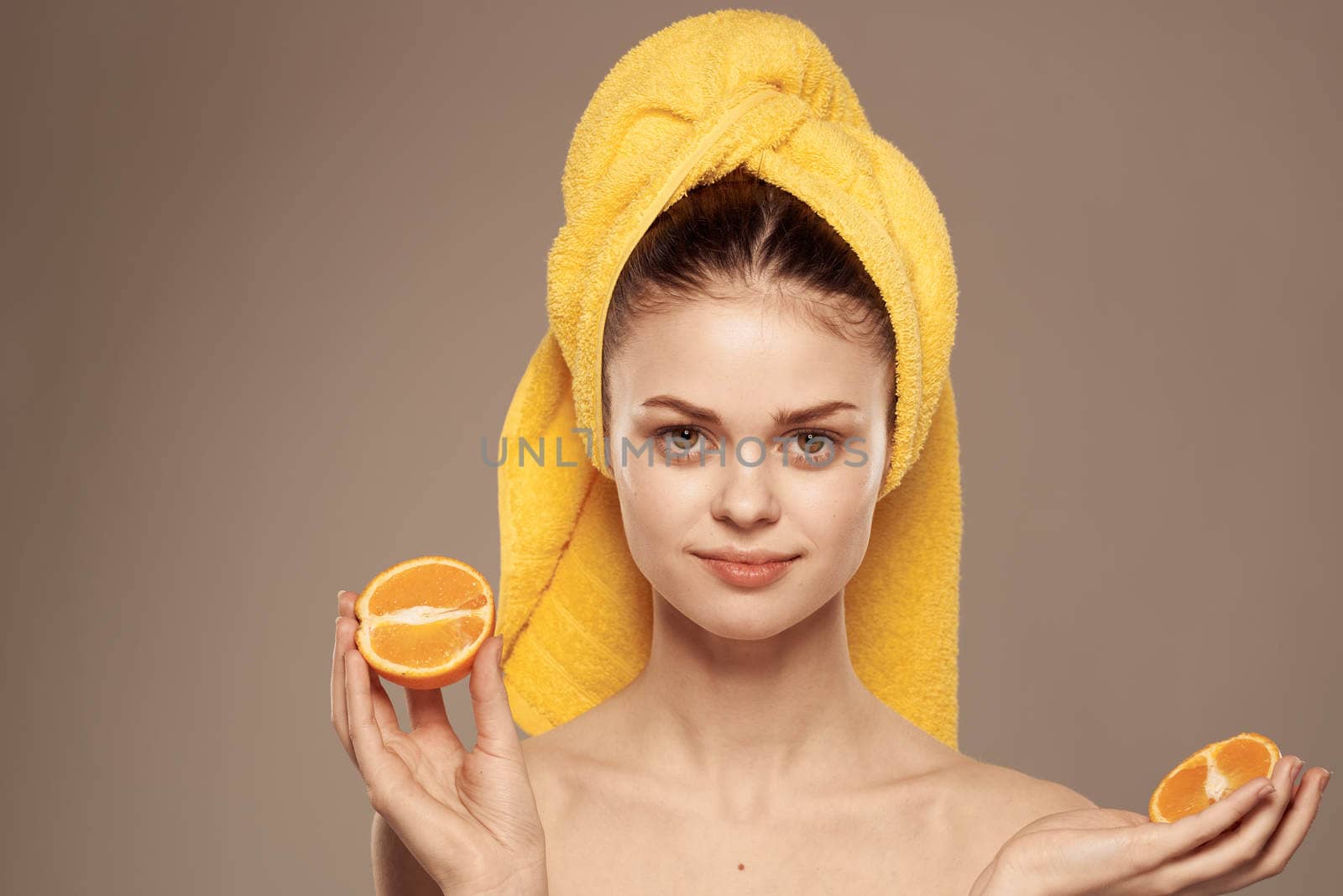 Woman with oranges in hands emotions naked shoulders towel on head beige background by SHOTPRIME