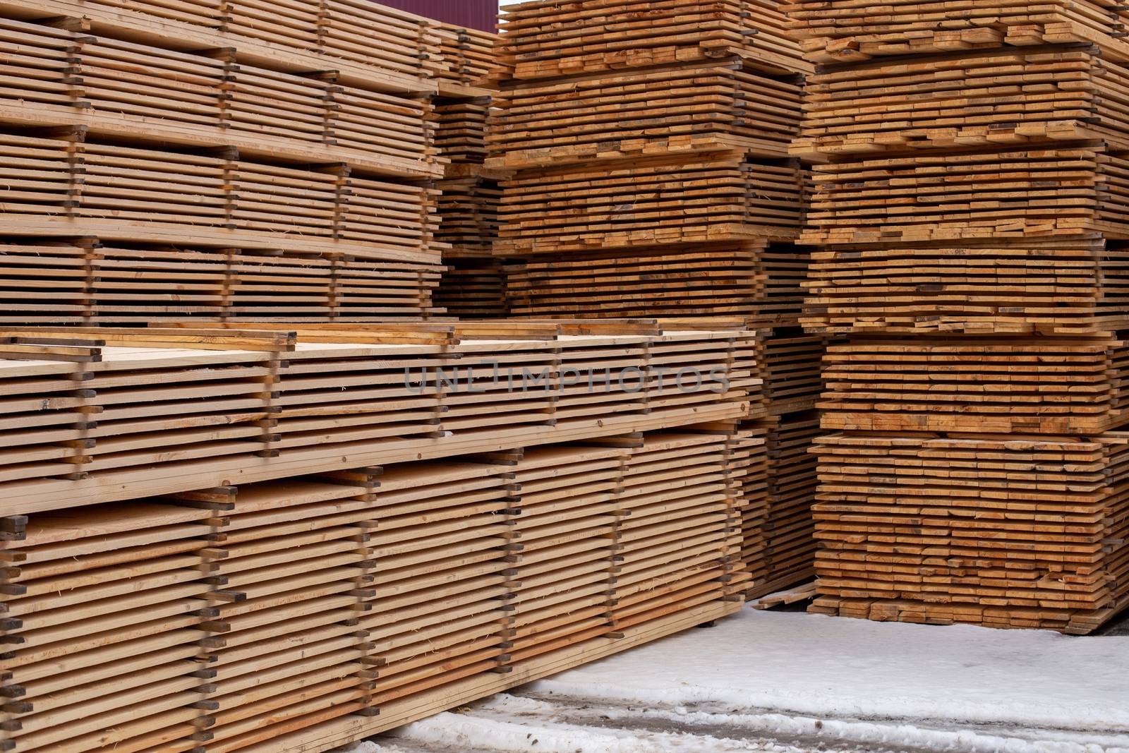 Large stacks of wooden boards background with inear perspective. Winter woodwork industrial storage.